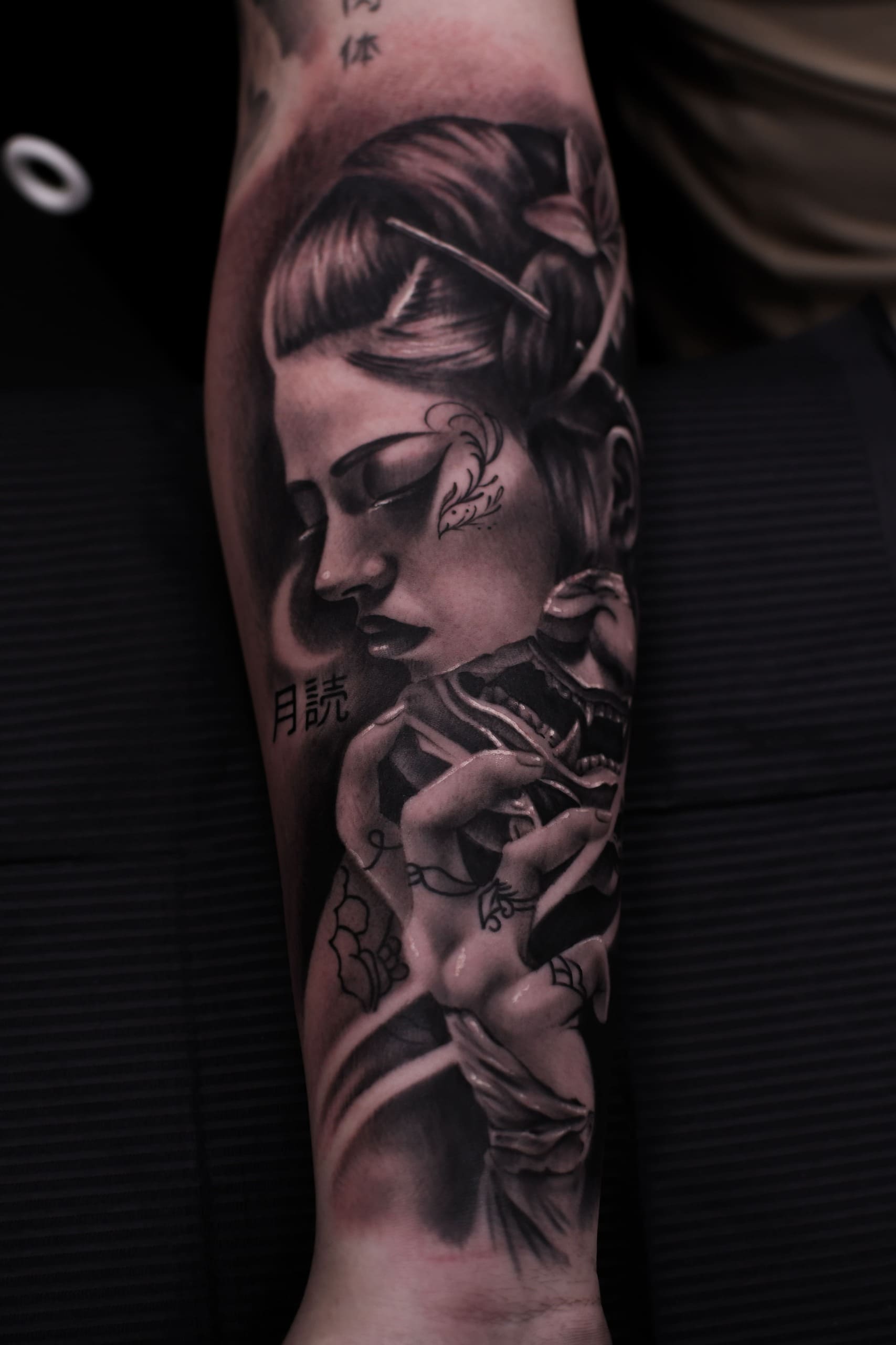 Tatouage réalisme noir et gris avant-bras japonais masque Oni et Geisha